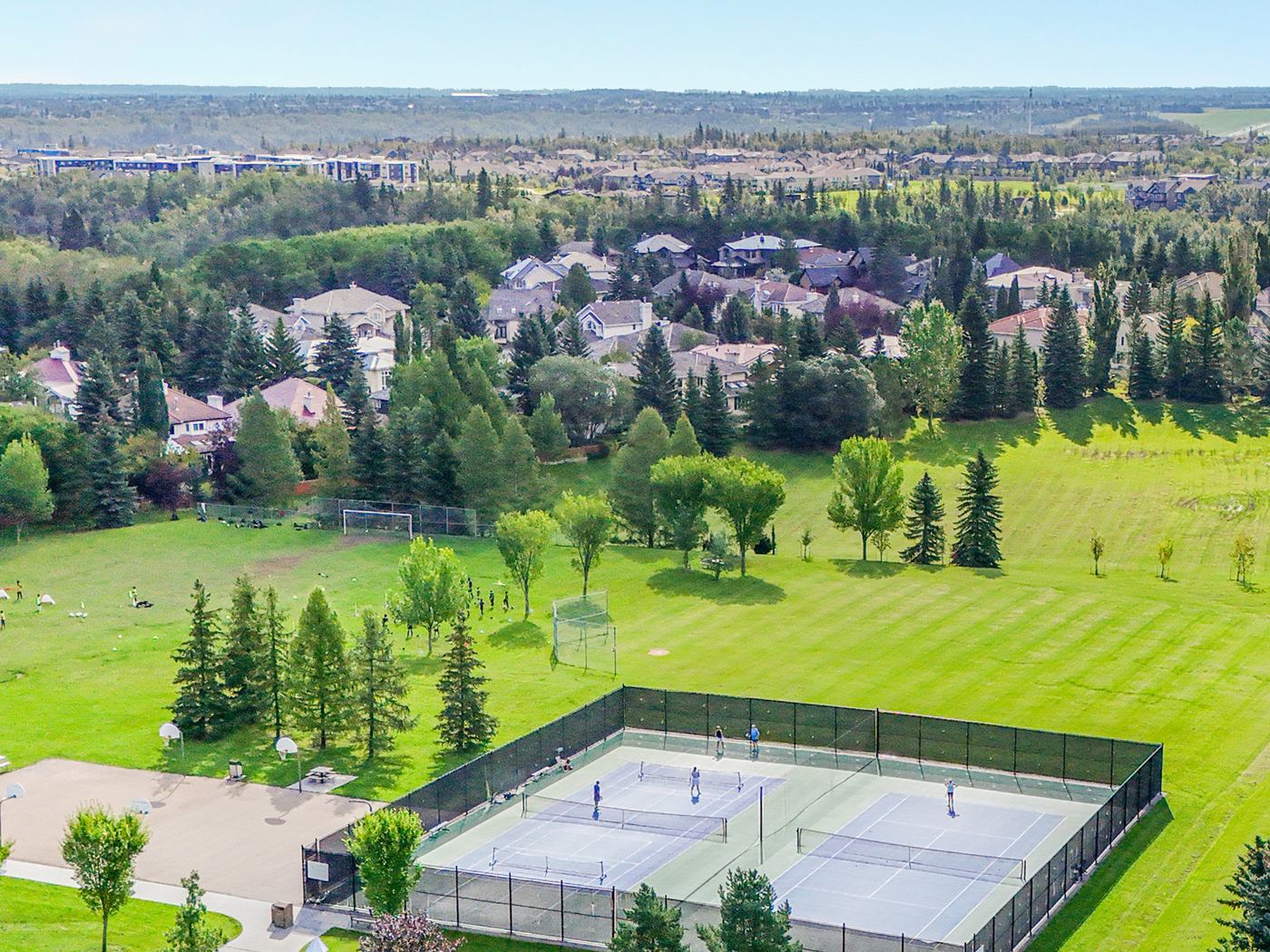 Aerial view of the community tennis and pickleball courts in use, the sports field and the houses beyond.