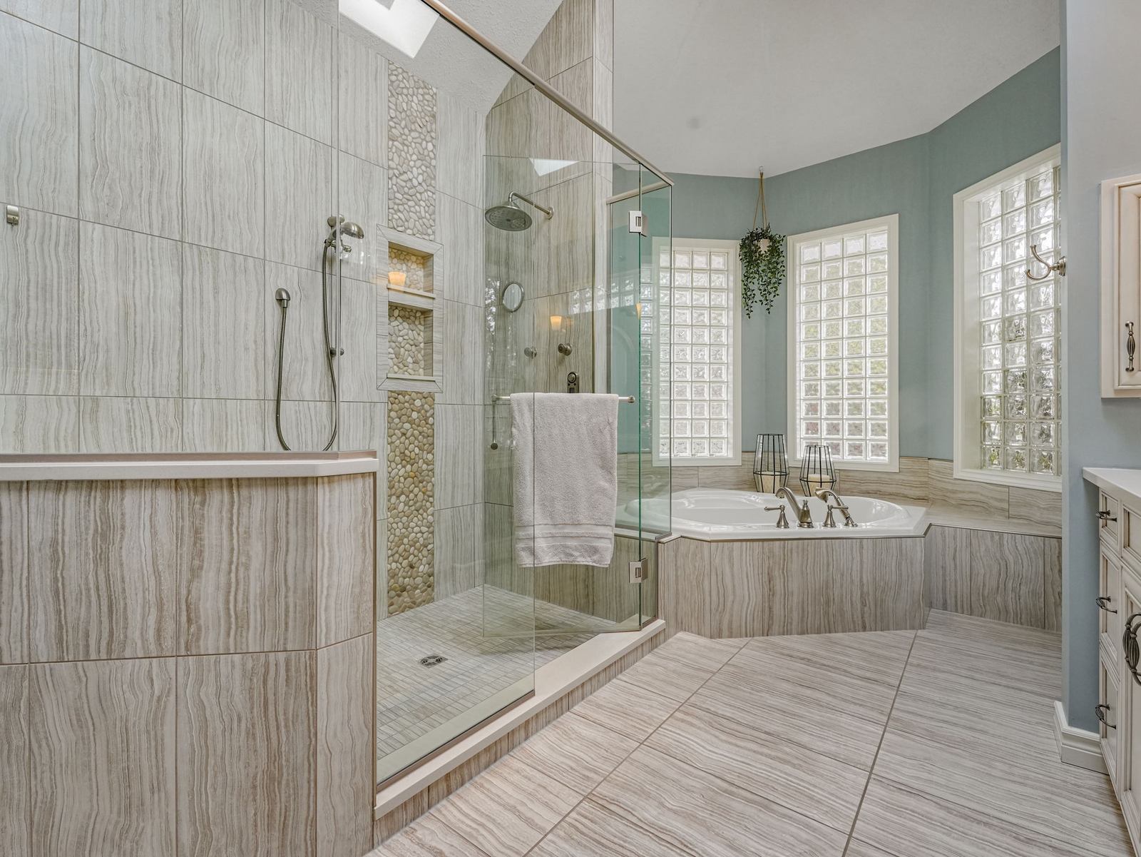 The five-piece ensuite with a glass multi-jet shower, corner jetted tub and glass block windows under a skylight.