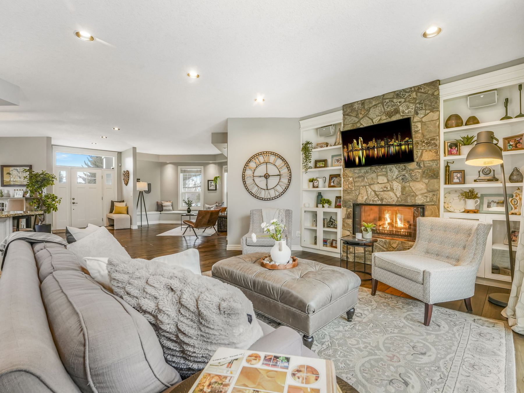 The main floor family room with a lit gas fireplace set into a hand-laid stone surround, flanked by built-in shelving.