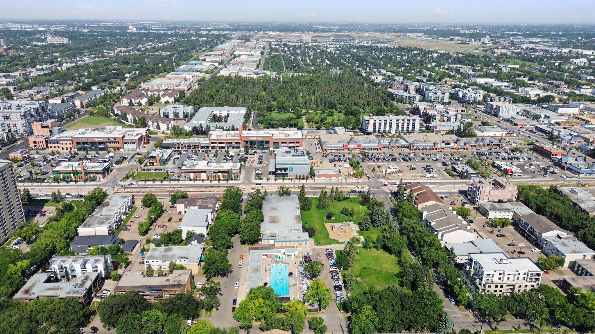 Aerial view of the Brewery District shopping area and the surrounding low-rise neighbourhood, with a park and outdoor pool in the middle distance.