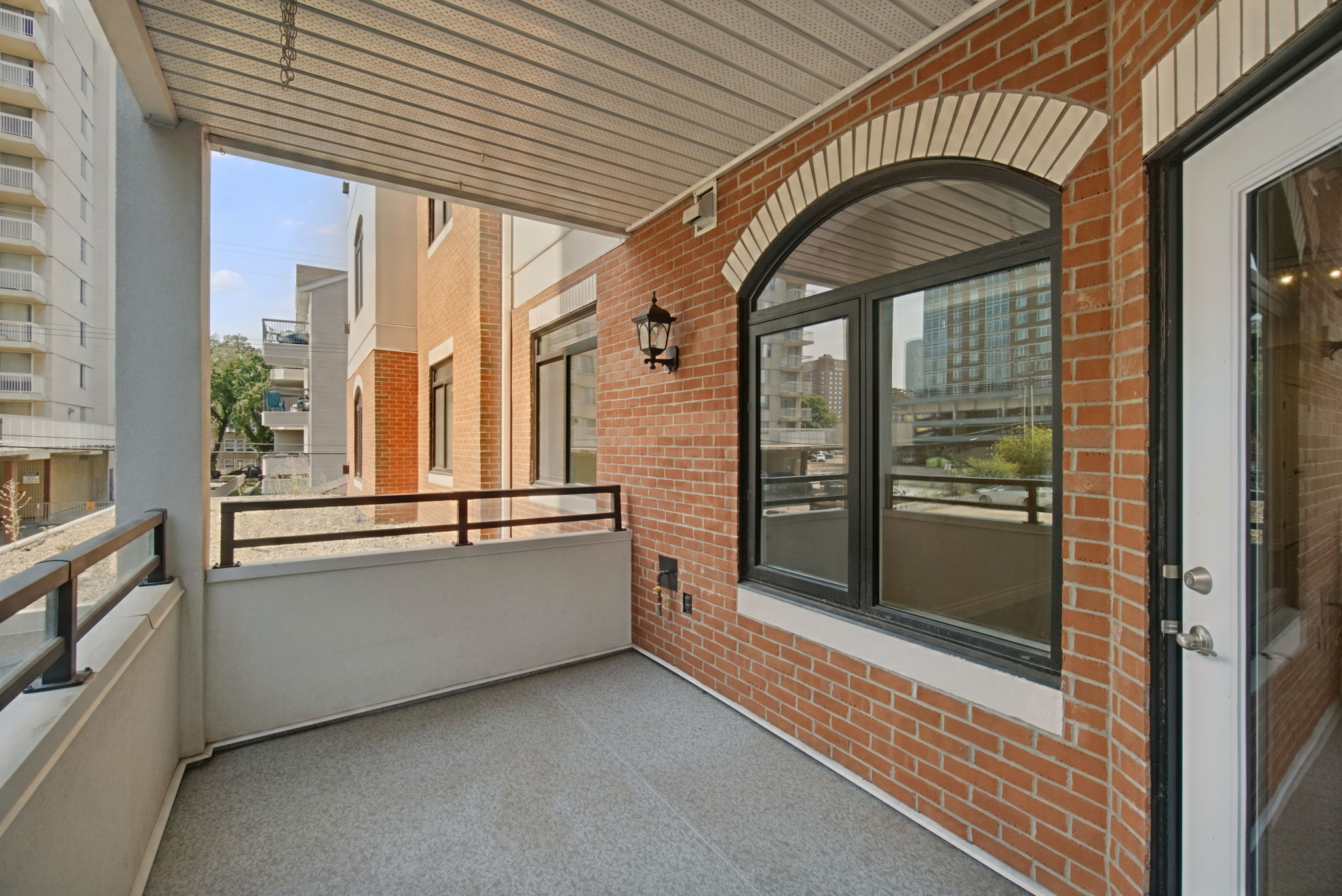 The covered balcony looking out over the railing to the neighbouring buildings and trees.