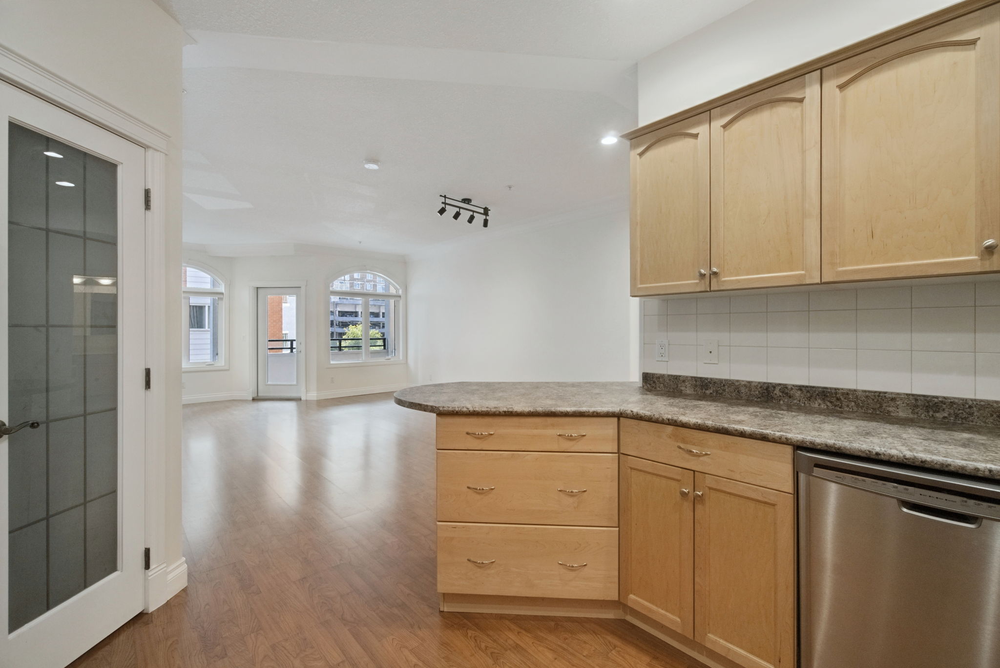 The kitchen peninsula looking out over the living room toward the arched windows and balcony door.