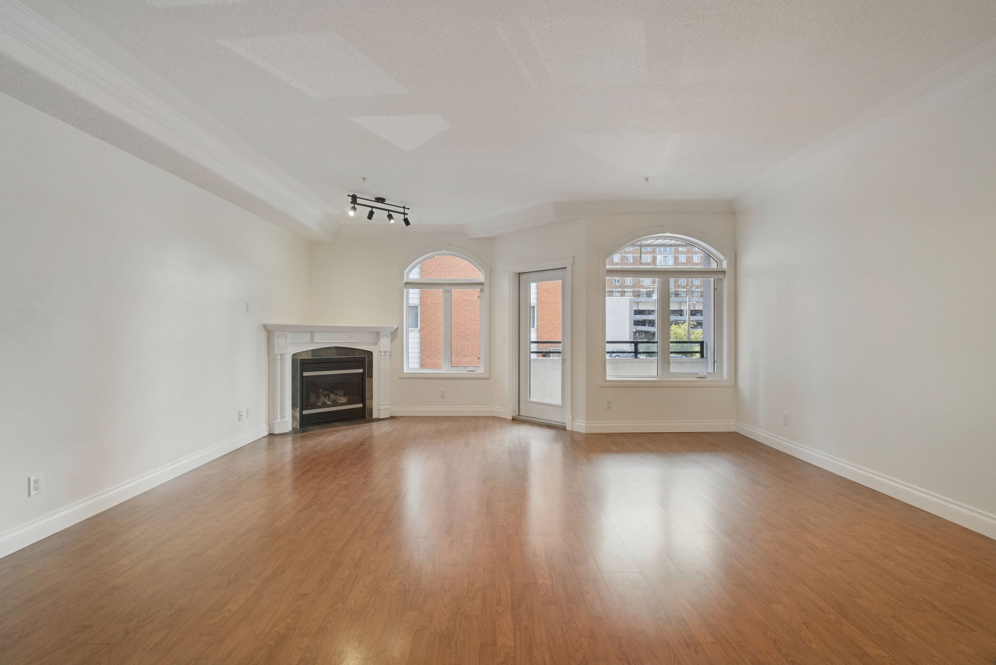 The living room looking toward the two arched windows and the balcony door, with the fireplace on the left.
