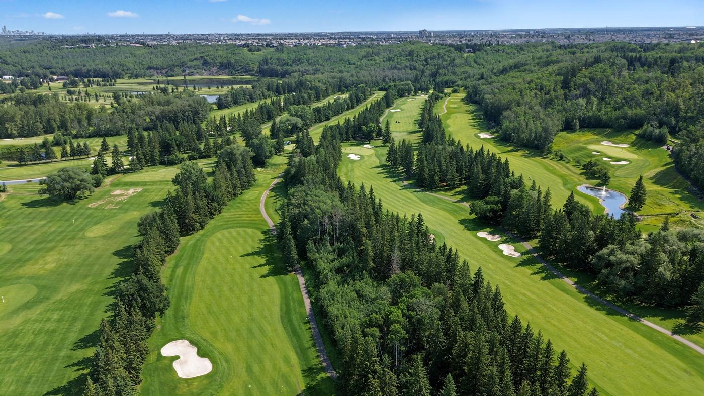 Fairways and bunkers of a golf course laid out along the wooded river valley.