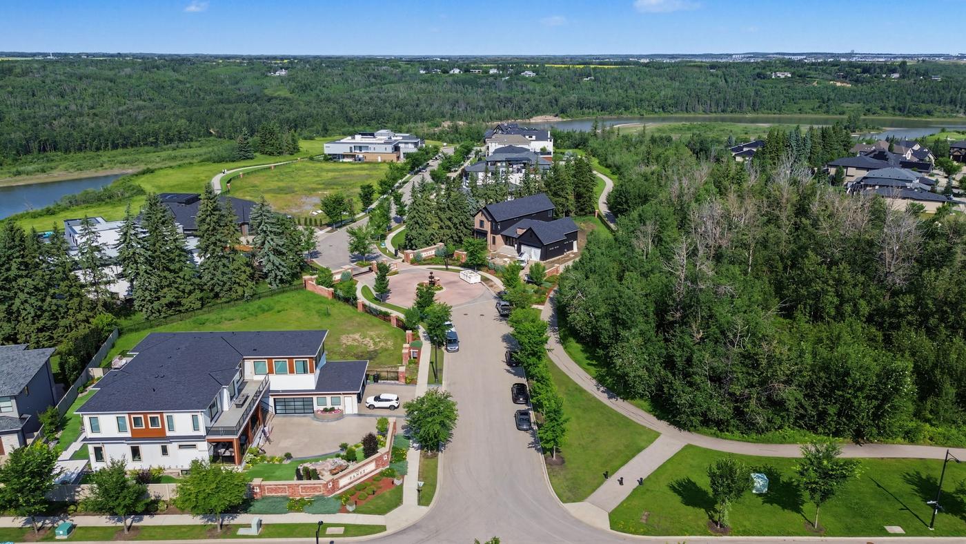 Streetscape within The Banks showing large custom homes on a curving road backing onto trees.