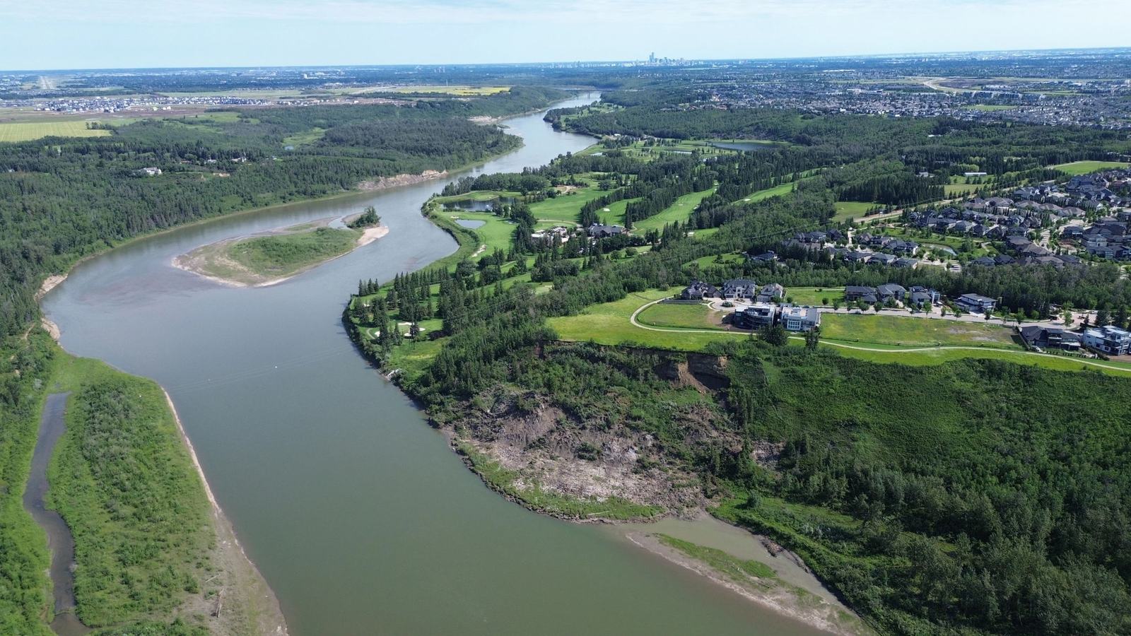 The North Saskatchewan River winding through a wooded valley with the Edmonton skyline on the horizon.